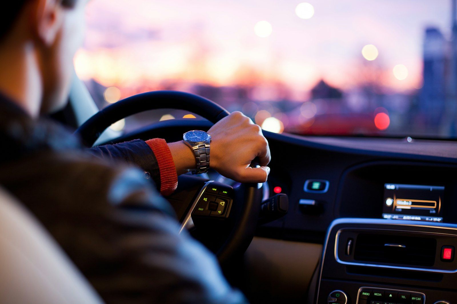 Chauffeur driving a car through city streets at dusk