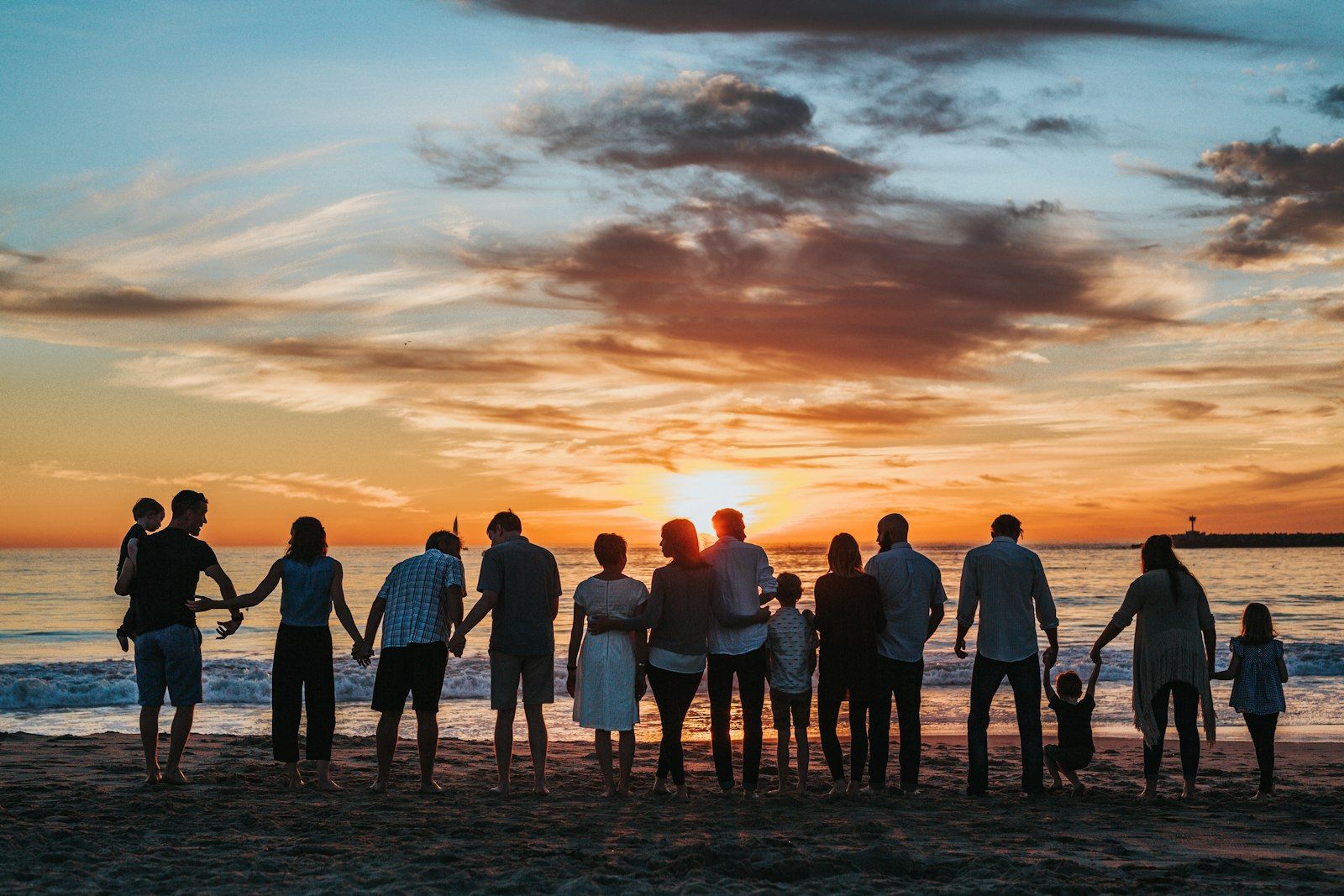 Family standing together on a beach at sunset during a holiday